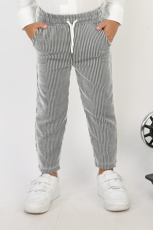 Siyah beyaz dikey çizgili, beli lastikli ve ipli, fitilli kumaş erkek çocuk pantolonu.