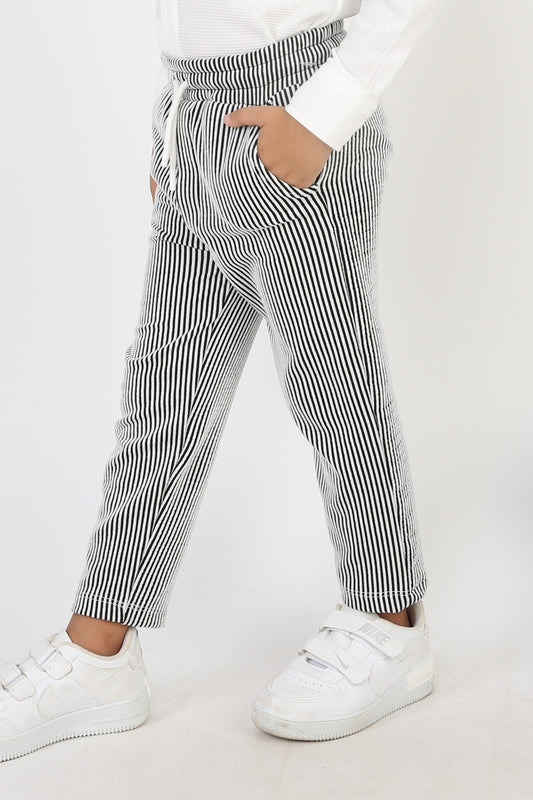 Siyah beyaz dikey çizgili, beli bağcıklı ve fitilli kumaştan erkek çocuk günlük pantolon.