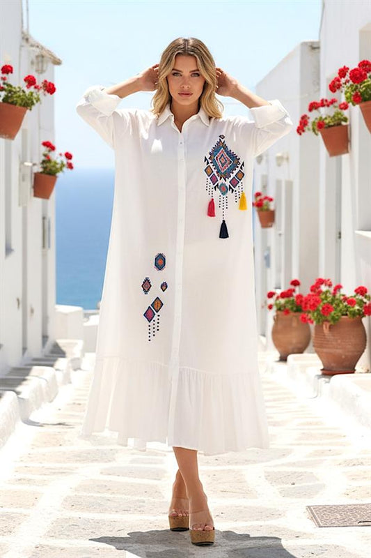 Beyaz, önü ve eteği nakışlı, püsküllü, fırfırlı etekli, uzun kollu gömlek elbise.