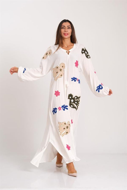 Beyaz renkli, uzun kollu, nakış detaylı ve püskül bağlamalı uzun viskon elbise.