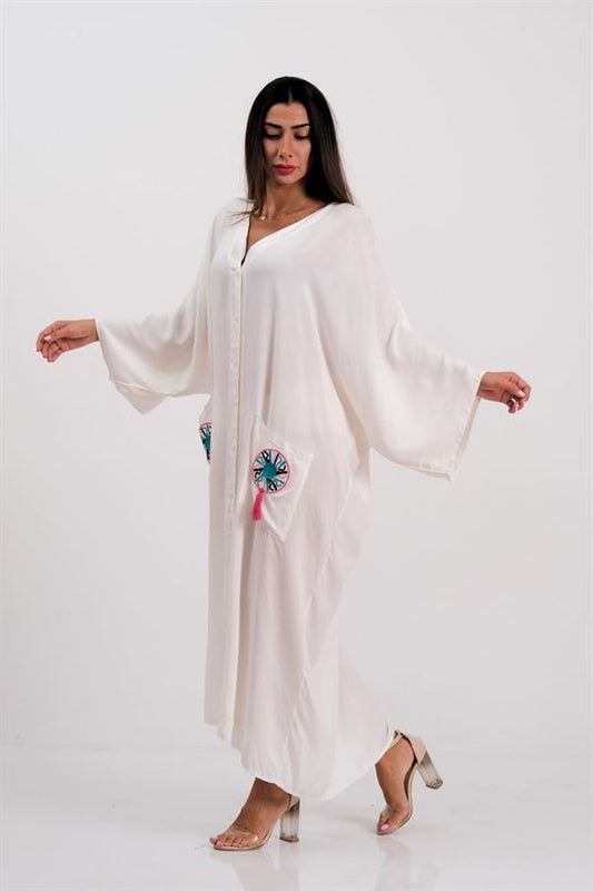 Beyaz V yaka, cepleri nakışlı ve püsküllü, düğmeli, oversize uzun viskon elbise.