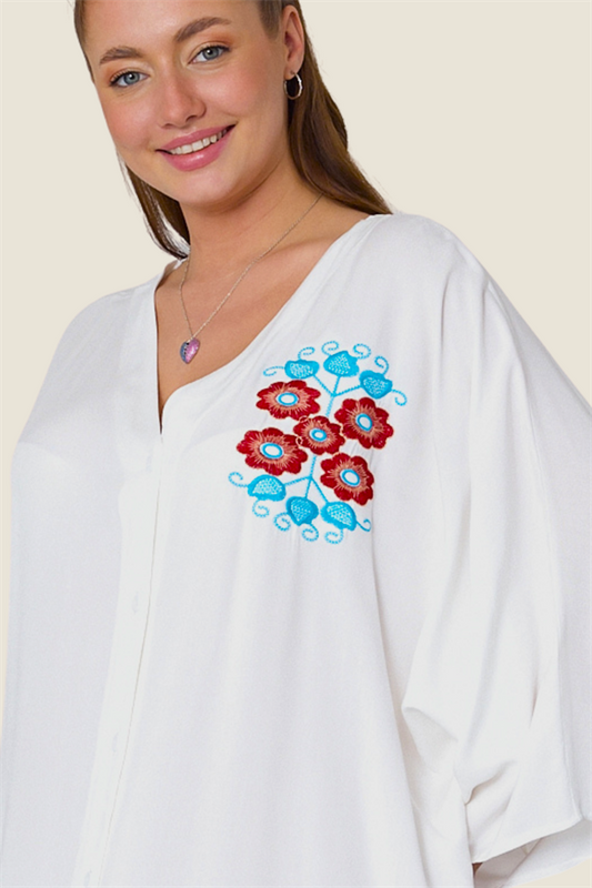 Göğüs kısmında renkli çiçek nakışları bulunan beyaz V yaka oversize gömlek elbise.