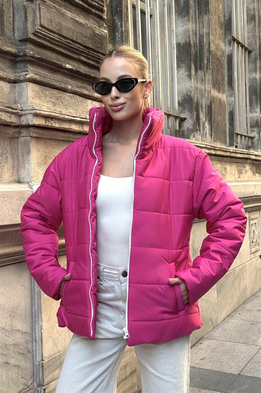 Fuşya rengi, dik yakalı, fermuarlı ve şişme tasarımlı kadın mont.