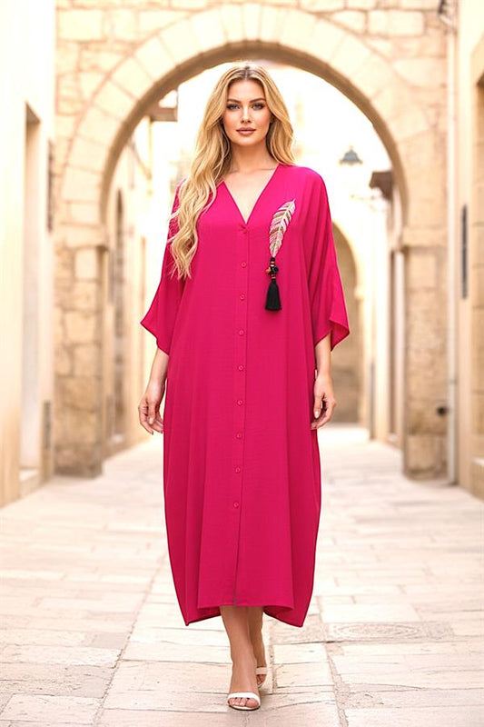 A model wears a fuchsia V-neck oversized long dress with feather embroidery and tassel details.