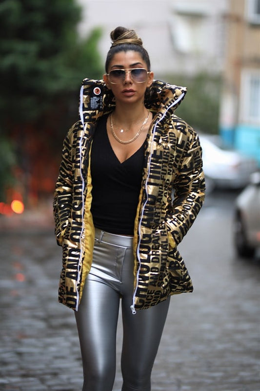 Siyah yazılı desenlere sahip, dik yakalı, uzun ve parlak gold şişme mont.