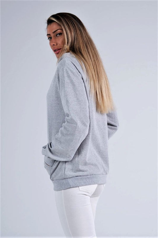 Gri renkli, kapüşonlu, kanguru cepli ve şardonlu sweatshirt giyen bir kadın.
