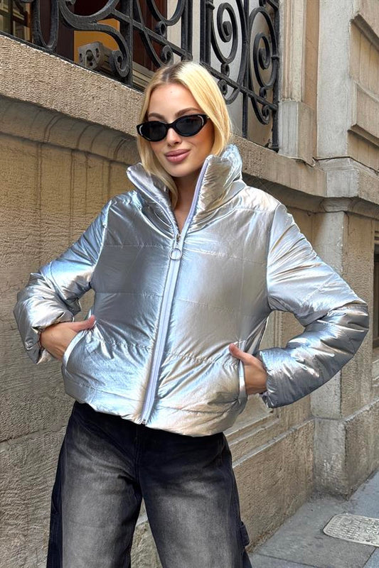 Gümüş renkli, dik yakalı, parlak ve kısa şişme mont.