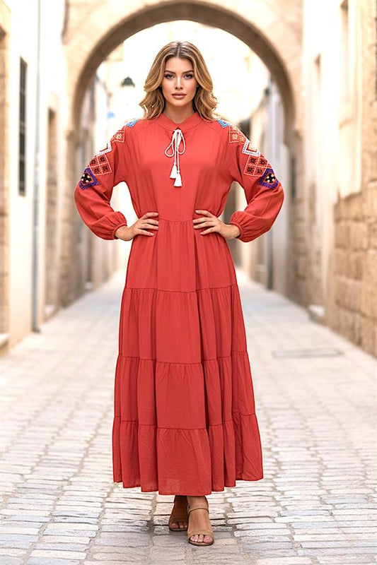 Kiremit rengi, sıfır yaka, kolları nakışlı ve kat kat etekli uzun viskon elbise.