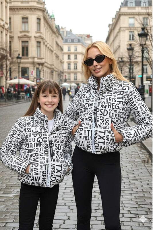 Üzerinde siyah yazılar bulunan beyaz şişme mont giymiş bir kız çocuğu.