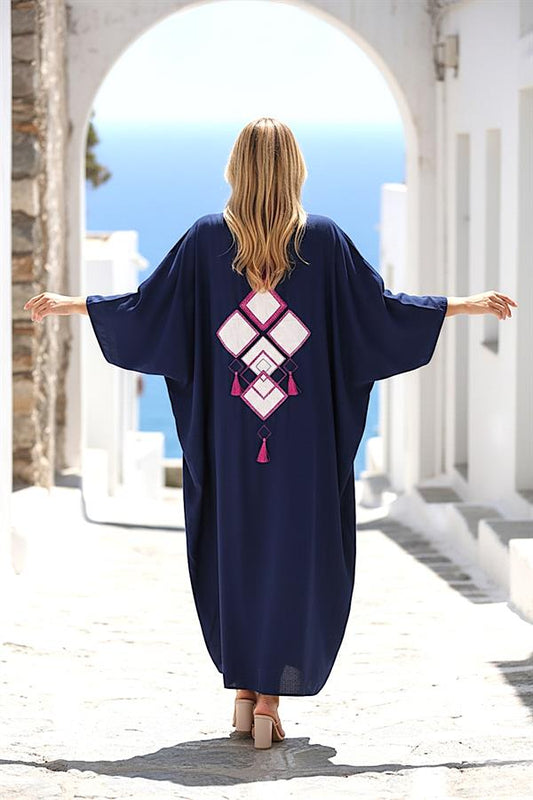 Sırtında beyaz geometrik nakış ve püskül detayları bulunan lacivert oversize uzun gömlek elbise.