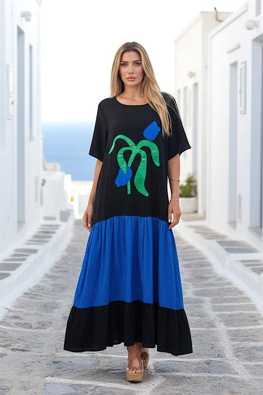 Siyah ve mavi renkli, kısa kollu, lale aplikeli ve katlı etekli uzun viskon elbise.