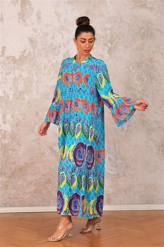 Mavi renkli, volanlı kollu, önden düğmeli ve kat kat etekli tropikal desenli uzun elbise.