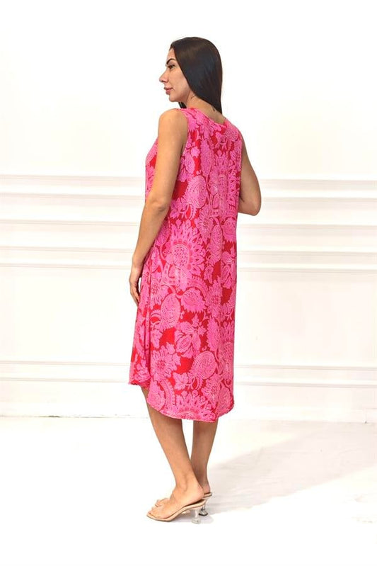 Pembe desenli, kalın askılı ve midi boy viskon elbise giyen bir kadın.