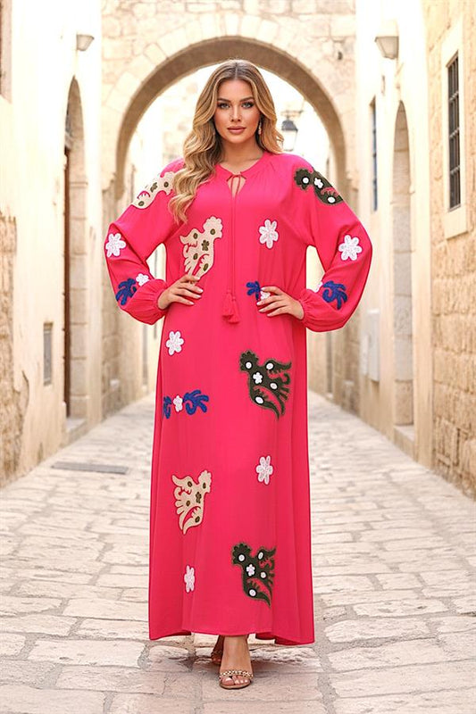 Pembe renkli, nakış detaylı, püskül bağlamalı ve uzun kollu viskon elbise.