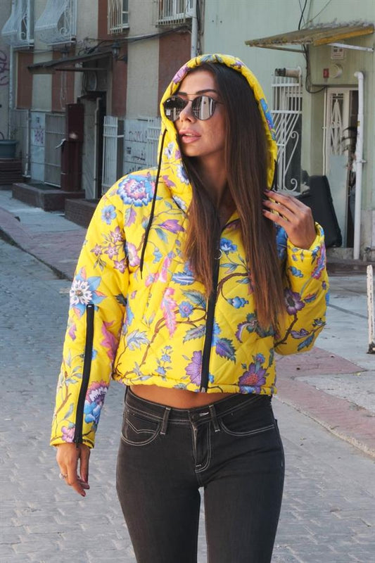 Sarı çiçek desenli, kapüşonlu, kolları fermuarlı ve kısa kesim şişme mont.