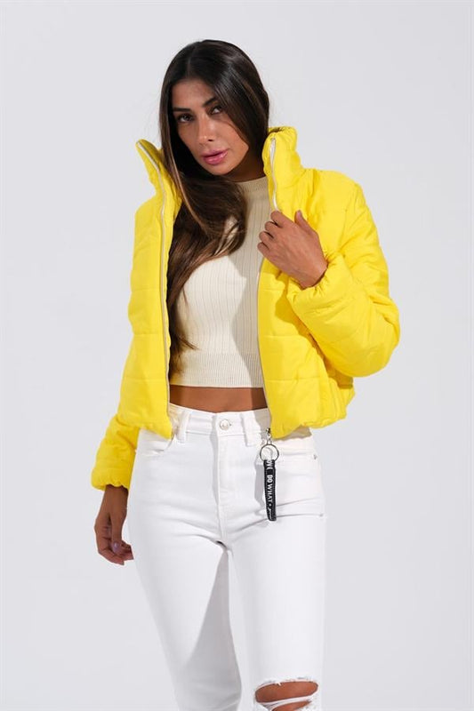 Sarı renkli, dik yakalı ve kısa kesim şişme mont giyen bir kadın.