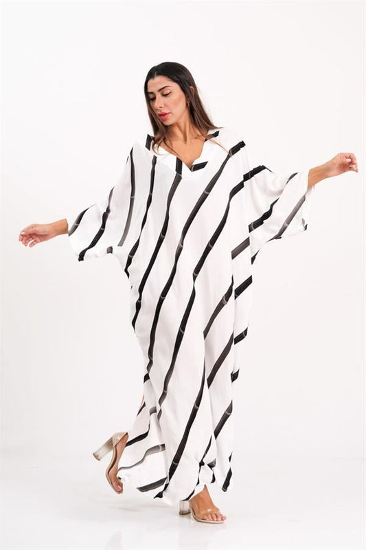 Siyah çizgili, V yakalı, yarasa kollu ve oversize kesim uzun beyaz elbise.