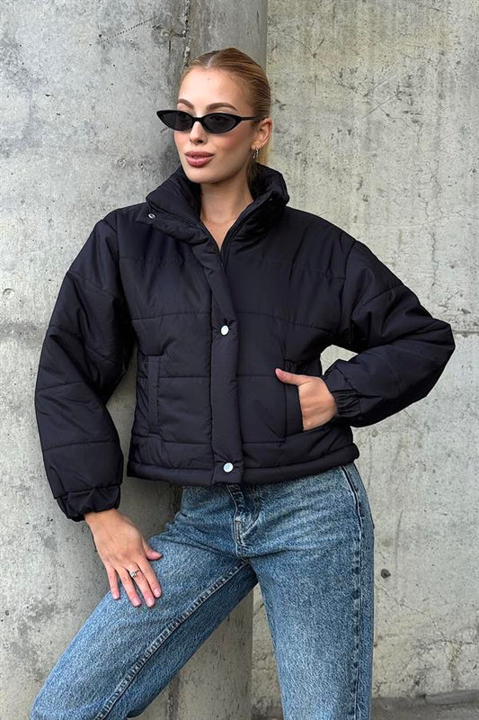 Siyah renkli, dik yakalı, çıtçıtlı ve fermuarlı kısa şişme mont.