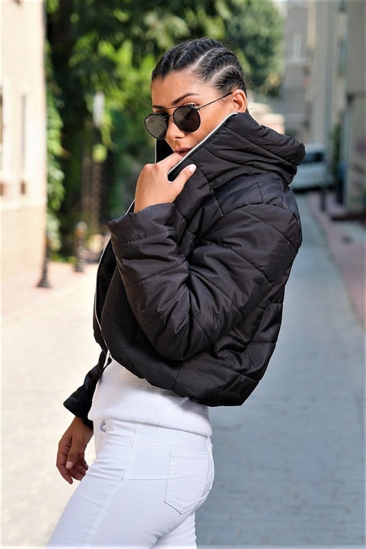 Siyah renkli, dik yakalı, kısa kesim ve su geçirmez kumaştan üretilmiş şişme mont.