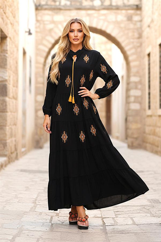 Siyah, önü ve kolları otantik nakışlı, püskül bağcıklı ve kat kat etekli uzun elbise.