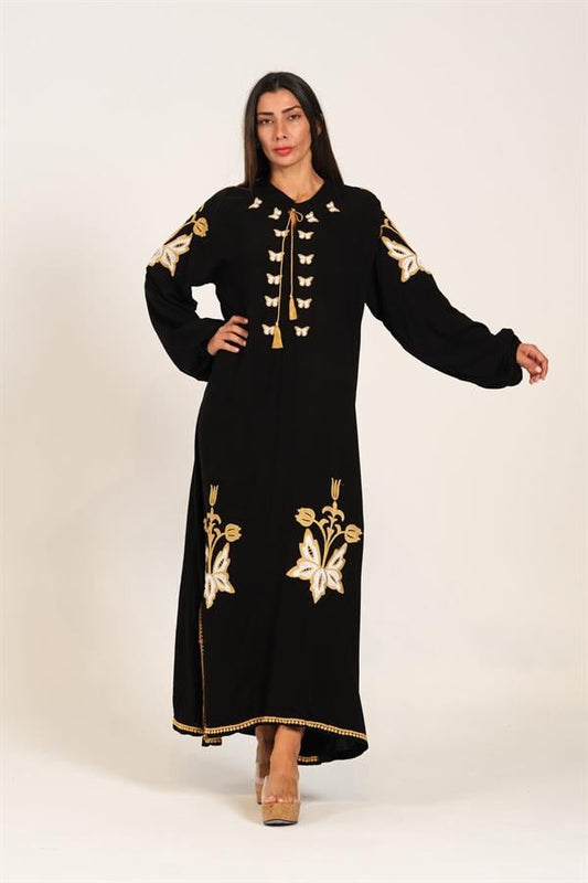 A woman wears a long black dress with balloon sleeves and authentic gold embroidery.
