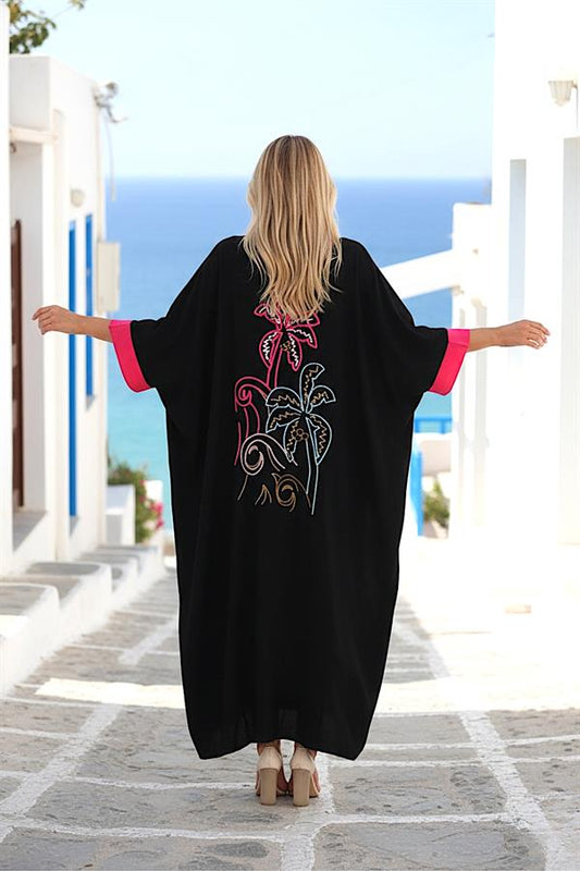 Sırtında palmiye nakışı bulunan, pembe detaylı, siyah yarasa kol uzun oversize elbise.