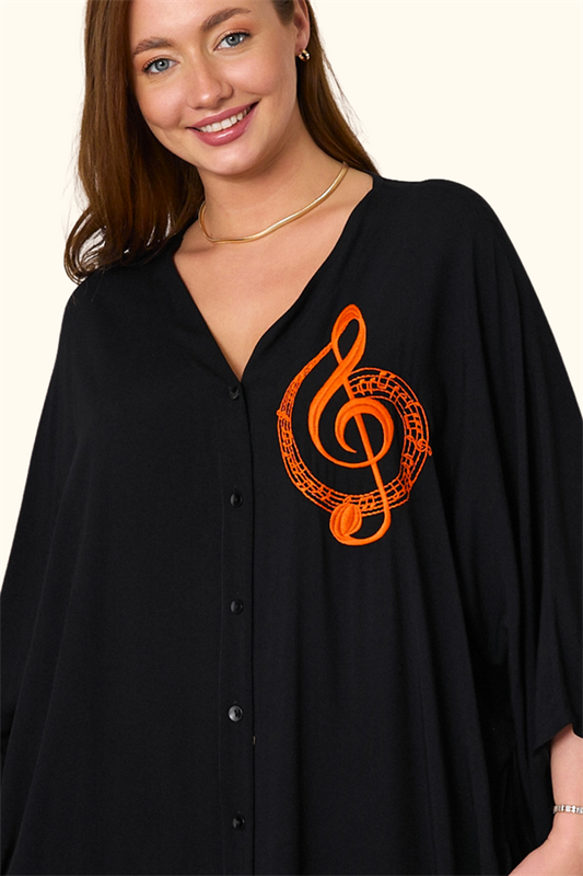 Siyah, V yaka, göğsünde turuncu nota nakışı bulunan, oversize kesim uzun gömlek elbise.