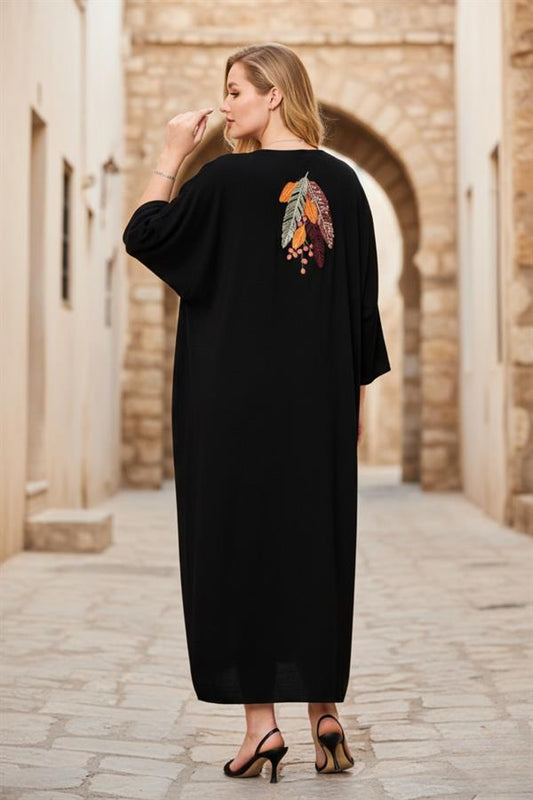 Sırtında tüy nakışlı detay bulunan, siyah renkli, oversize kesim uzun viskon elbise.