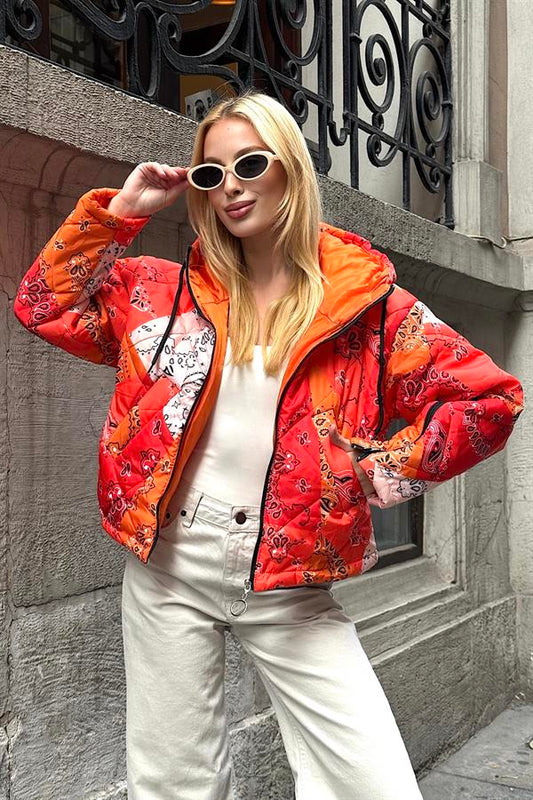 Turuncu desenli, kapüşonlu, kolları fermuarlı ve kısa kesim şişme mont.