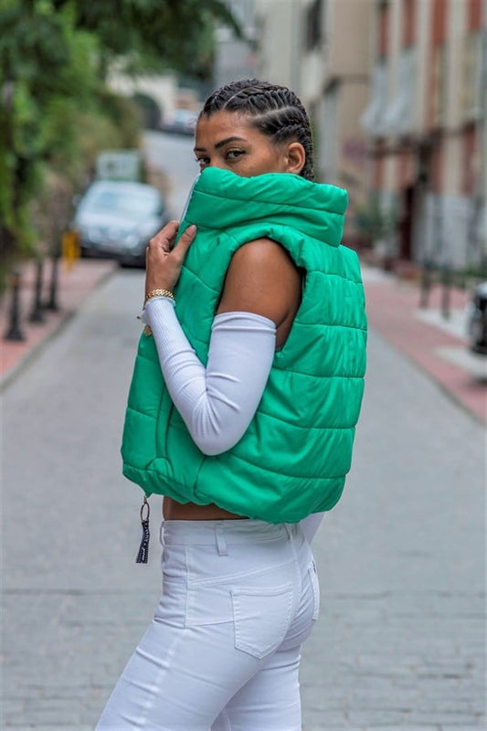 Yeşil renkli, dik yakalı, fermuarlı ve cepli kısa şişme yelek.