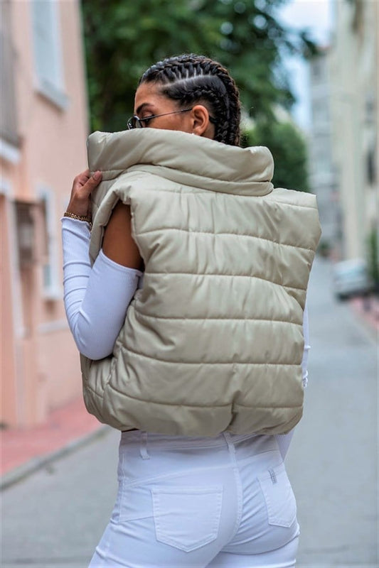 Bej renkli, dik yakalı, fermuarlı ve kısa kesim şişme yelek.