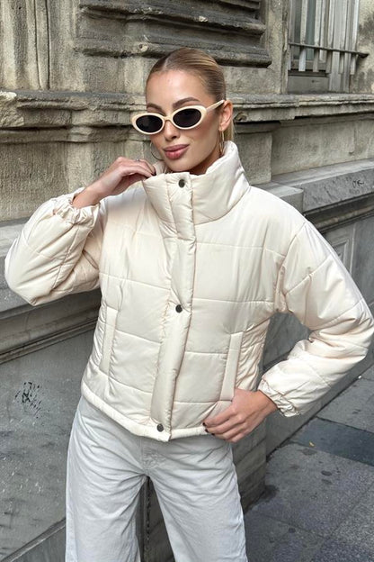 Bej renkli, dik yakalı, çıtçıtlı ve fermuarlı kısa şişme mont.