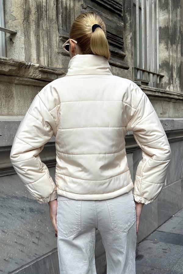 Bej renkli, dik yakalı, fermuarlı ve kısa kesim şişme mont.