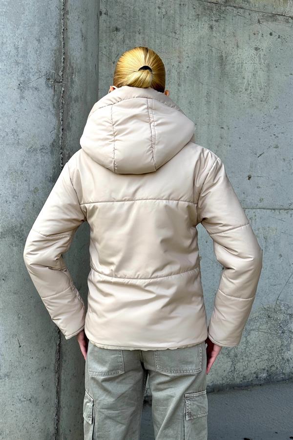 Bej renkli, kapüşonlu ve su geçirmez kumaştan üretilmiş şişme mont.