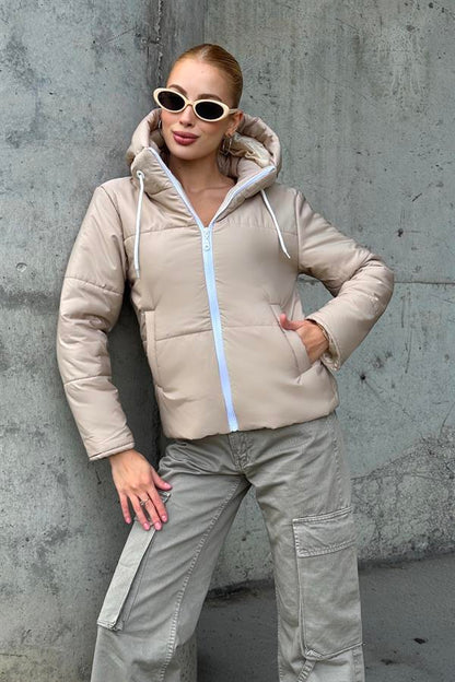 Bej renkli, beyaz fermuarlı ve kapüşonlu su geçirmez şişme mont.