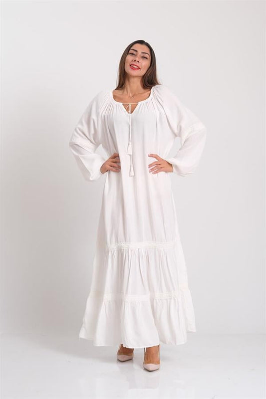 Beyaz, carmen yakalı, balon kollu, etekleri fistolu ve püskül detaylı oversize uzun elbise.