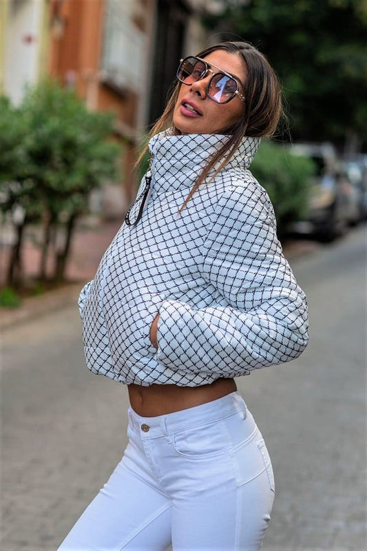 Beyaz renkli, dik yakalı, siyah desenli ve kısa kesim şişme mont.