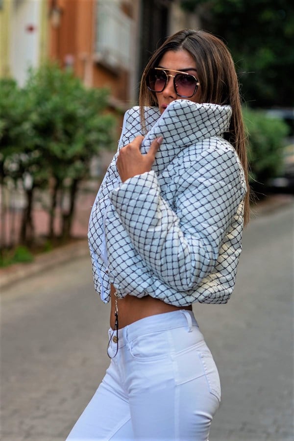 Beyaz renkli, dik yakalı, siyah desenli ve kısa kesim şişme mont.