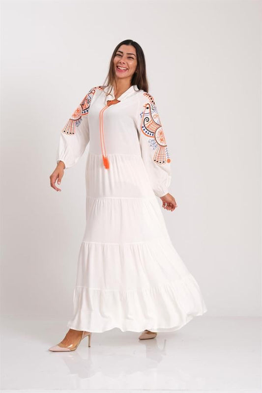 Beyaz, dik yakalı, kolları kuş nakışlı ve etekleri kat kat olan uzun viskon elbise.