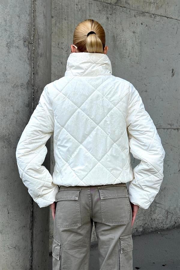 Beyaz şal desenli, dik yakalı, kısa ve kapitone dikişli şişme mont.