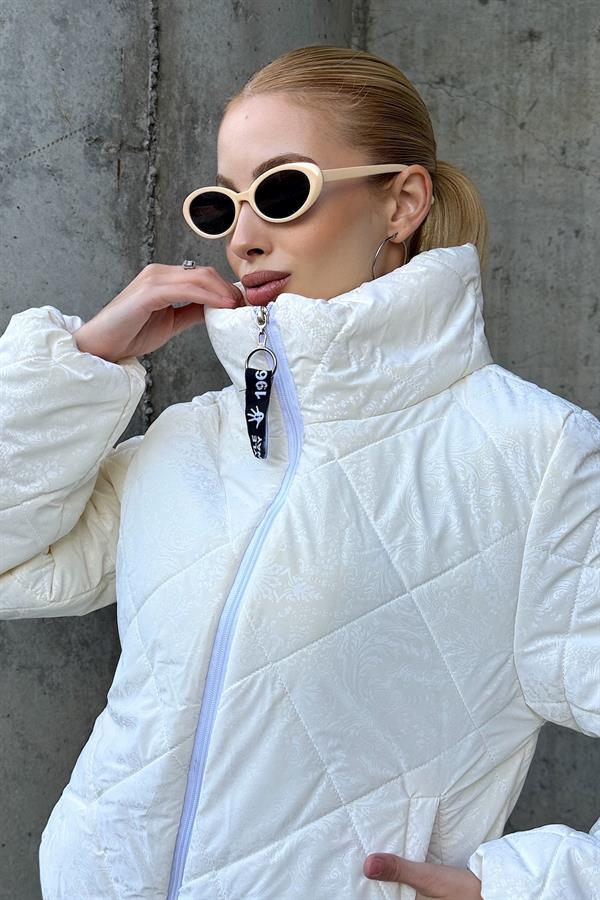 Beyaz şal desenli, dik yakalı ve fermuarlı kısa şişme mont.