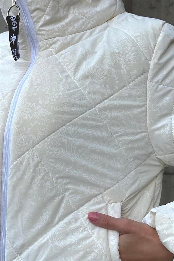 Beyaz şal desenli, dik yakalı ve fermuarlı kısa şişme mont.