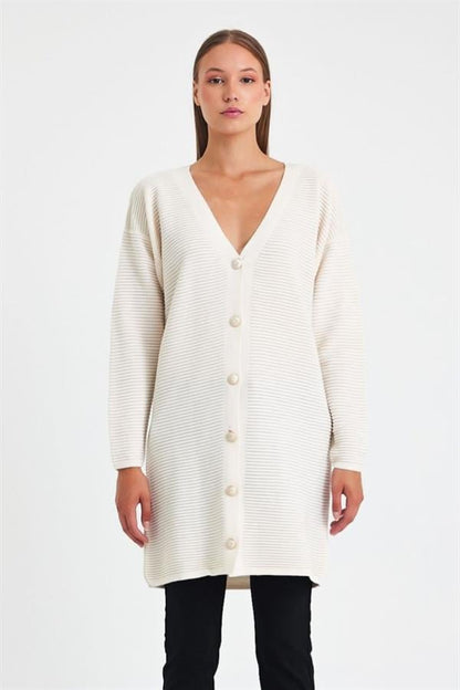 Beyaz renkli, fitilli dokuya sahip, düğmeli ve uzun triko hırka.