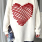 Beyaz renkli, üzerinde kırmızı kabartmalı büyük kalp deseni bulunan uzun kollu triko kazak.