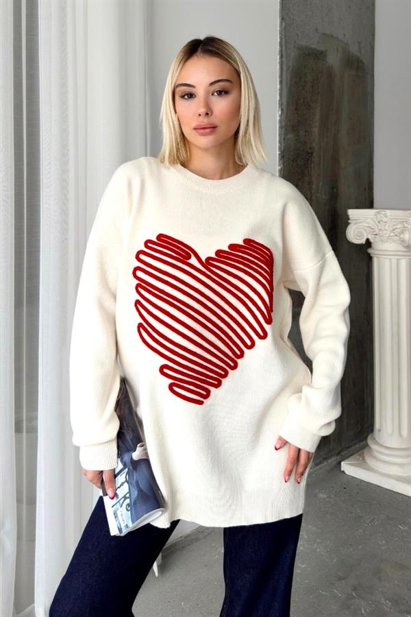 Beyaz renkli, üzerinde kırmızı kabartmalı büyük kalp deseni bulunan uzun triko kazak.