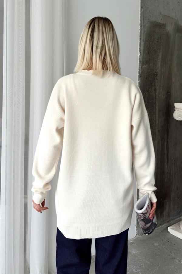 Sırtı düz beyaz renkli, uzun kollu ve triko kumaştan üretilmiş standart beden kazak.