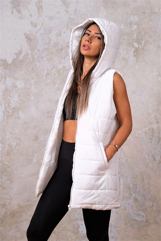 Beyaz renkli, kapüşonlu, cepli ve kolsuz şişme yelek giyen bir kadın.