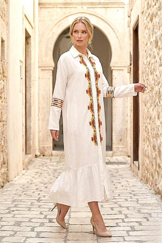 Beyaz, önü ve kolları nakışlı, etek ucu fırfırlı, uzun kollu gömlek elbise.