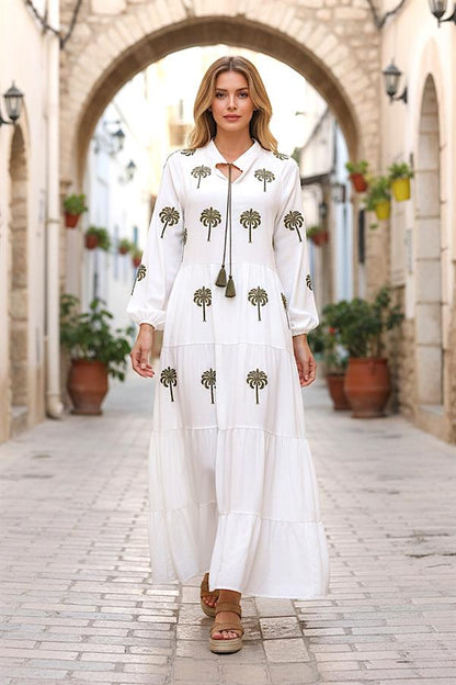 Beyaz, önü ve kolları palmiye nakışlı, püskül bağcıklı, kat kat uzun viskon elbise.