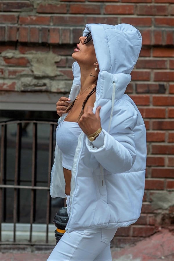 Beyaz renkli, kapüşonlu ve su itici kumaştan üretilmiş şişme mont.